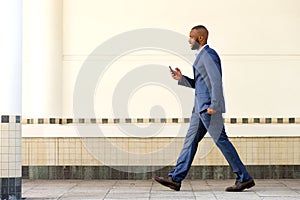 Side portrait of young african business man walking with mobile phone