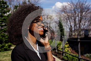 Side portrait of the young attractive african businesslady i neyeglasses happily talking o nthe mobile phone. photo
