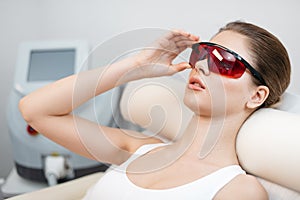 The side portrait of the young attractive woman with natural make-up wearing the safety goggles while lying in beauty
