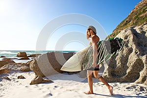 Side portrait of young man with surfboard walking on beach