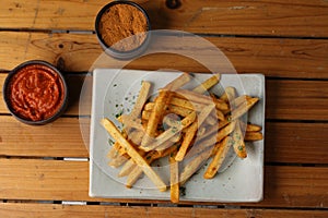 A side of potato fries with tomato and chilly sauce.