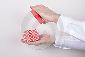 Side profile close up photo portrait of hands holding open unpack unwrap present box in hands isolated grey background