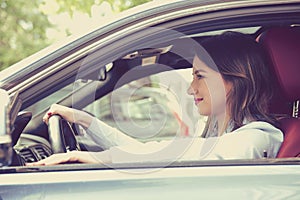 Side profile happy woman driving a modern car