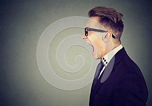 Side profile portrait of an angry young business man screaming