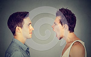 Side profile portrait of young angry man screaming at a calm smiling guy