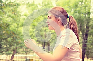 Side profile running young woman. Female runner jogging during outdoor workout