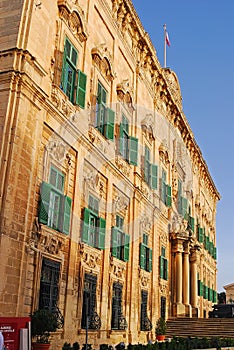 Side profile view of Auberge de Castille with iconic green windows & flag, now houses Office of Prime Minister in Valletta, Malta