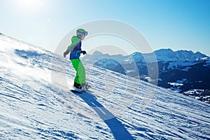 Side profile view of snowboarder boy go downhill in the mountain