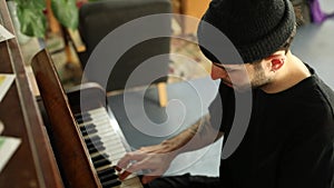 Side profile view of young man sitting on an old classic piano and playing some tunes