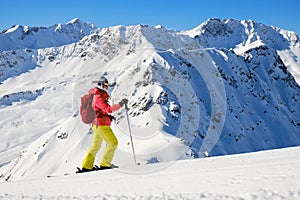 Side profile of a woman skier with colorful sport clothing against snowy mountain peaks in Arosa Lenzerheide ski resort.