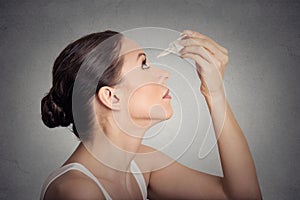 Side profile young woman applying eye drops