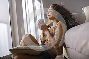 Side profile of a young woman drinking cup of tea at home