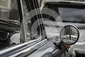 side rear rear view mirror of a classic vintage retro car. Old black vehicle with chrome details vintage round side view mirror