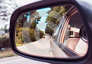 Side rear-view mirror on a car. Reflection of road at the car side mirror. Look in the rear view mirror of a vehicle