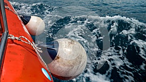 Side of the red life saving rescue boat sailing in cold ocean waves.