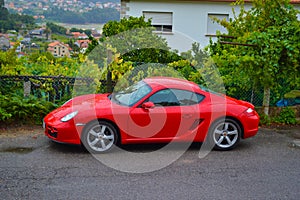 Side of a red Porsche Cayman 2.7 sport car, parked in a road o