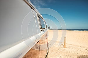 Side of a red vintage van parked on the beach in Fuerteventura