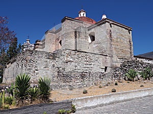 Side of San Pedro church in Mitla city, cobble road at archeological site of Zapotec culture on Oaxaca landscape, Mexico