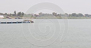 From the side, a sand barge loaded with sand can be seen traversing the Mekong river