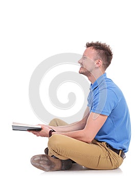 Side of a seated young man holding a book