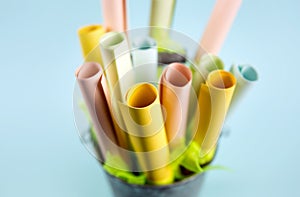 Side shallow depth of field view of pastel color paper rolls in container with copy space