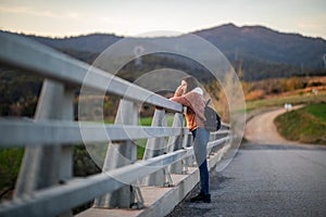 Side shot of a beautiful woman leaning on a metal fence during sunset