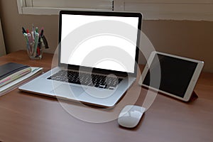 Side shot of computer laptop putting on wooden table with notebook, marker pen, mouse and tablet. Orderly workplace concept