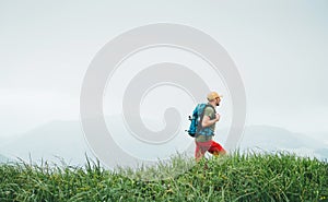 Side shot of hiker man walking by the foggy cloudy weather mountain range path with backpack. Active sport backpacking healthy