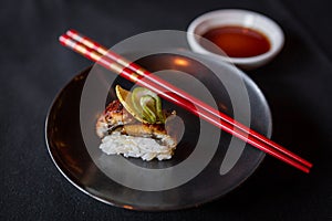 Side Shot of Sushi on Black Plate with Red Chopsticks