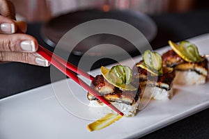 Side Shot of Sushi Picked Up With Red Chopsticks.