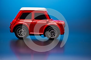 Side side; view of Red colored little toy model car on a blue background