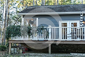 Side of small blue gray mobile home with a front and side porch with white railing