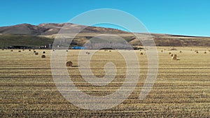 Side span of drone along countryside field with haystacks