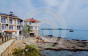 Side, Turkey, November 2019: Sailboat with lowered in the Mediterranean sea sails along a coast with apartment hotel