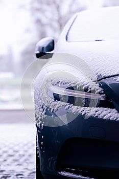 The side of a vehicle starting to get snowed under during a blizzard. The snow already covers the windshield of the car making it