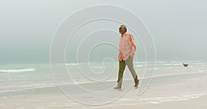 Side view of active senior African American man with hand in pocket walking on the beach 4k