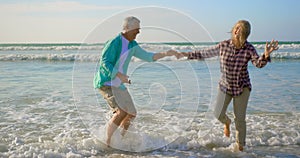 Side view of active senior Caucasian couple dancing together on the beach 4k