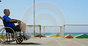 Side view of active senior Caucasian woman pushing senior man on wheelchair at beach 4k