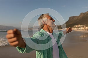 Senior man standing with arms outstretched on the beach