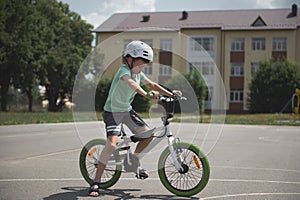 Side view active sporty boy in sports helmet confidently riding bike. A school age child cycling on city asphalt road
