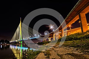 Side view of Ada bridge at night with reflection over Belgrade marina on Sava river