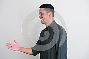 Side view of Adult Asian man smiling confident while going to hand shake with someone