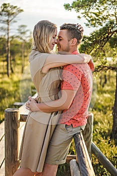 side view of affectionate couple hugging on wooden bridge with green plants