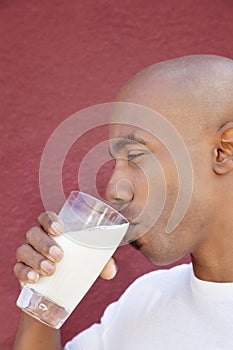 Side view of an African American man drinking milk over colored background