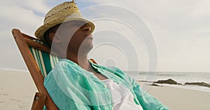 Side view of African american man sleeping in a sun lounger on the beach 4k