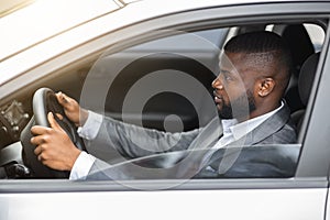 Side view of african american man in suit driving car