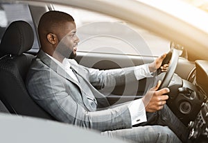 Side view of african american man in suit driving car