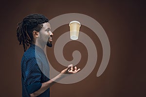 side view of african american man tossing up coffee in paper cup