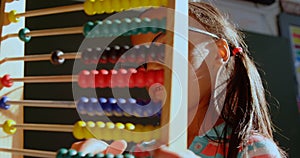 Side view of African American schoolgirl with spectacle learning math with abacus in classroom 4k