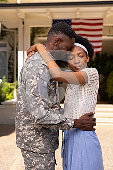 Side view of african american soldier husband embracing wife after returning home from army